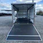 an ATC trailer with a black ramp parked in a gravel lot