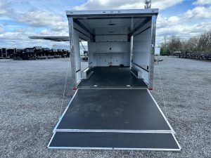 an ATC trailer with a black ramp parked in a gravel lot