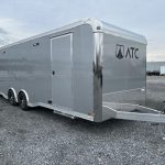 a gray trailer is parked in a gravel lot .