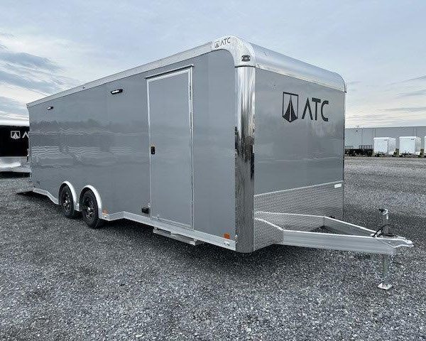 a gray trailer is parked in a gravel lot .