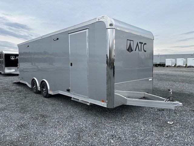 a gray trailer is parked in a gravel lot .