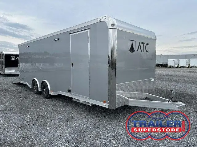 a gray trailer is parked in a gravel lot .