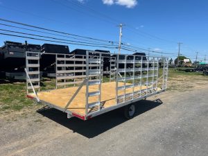 an Alcom trailer with a wooden deck parked on the side of the road