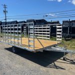 an Alcom trailer parked next to a row of dump trailers
