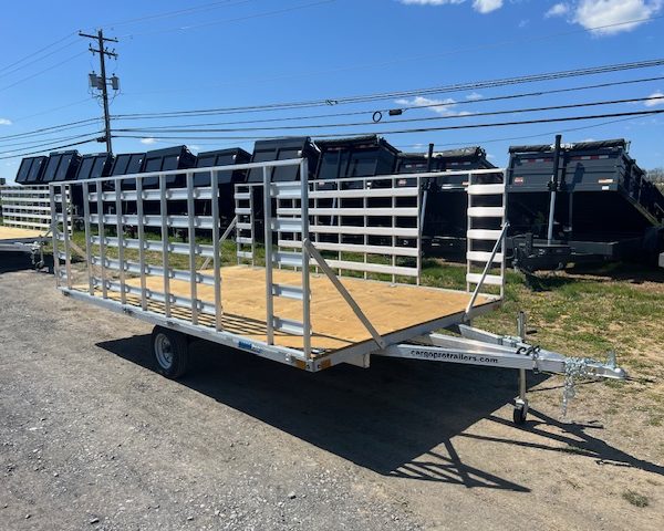 an Alcom trailer parked next to a row of dump trailers