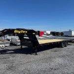 a big tex trailer is parked in a gravel lot .