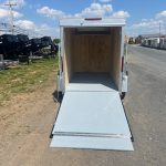 a white trailer with a ramp is parked on the side of the road .