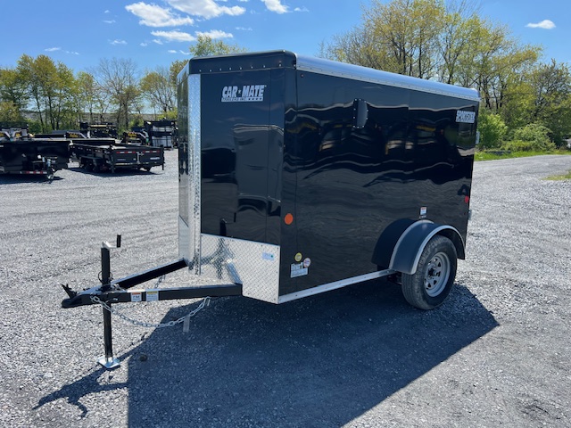 a black car-mate trailer is parked in a gravel lot