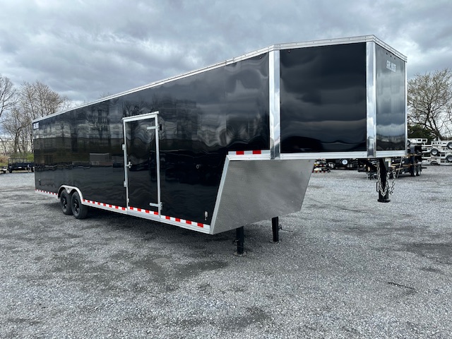 a black trailer is parked in a gravel lot .