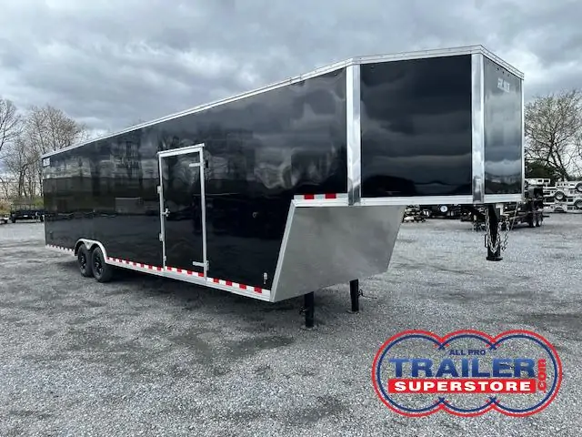 a black trailer is parked in a gravel lot .