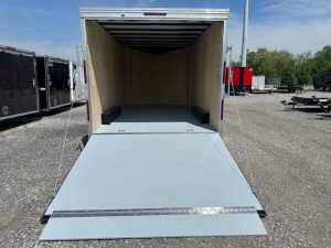 a trailer with a ramp is parked in a gravel lot .