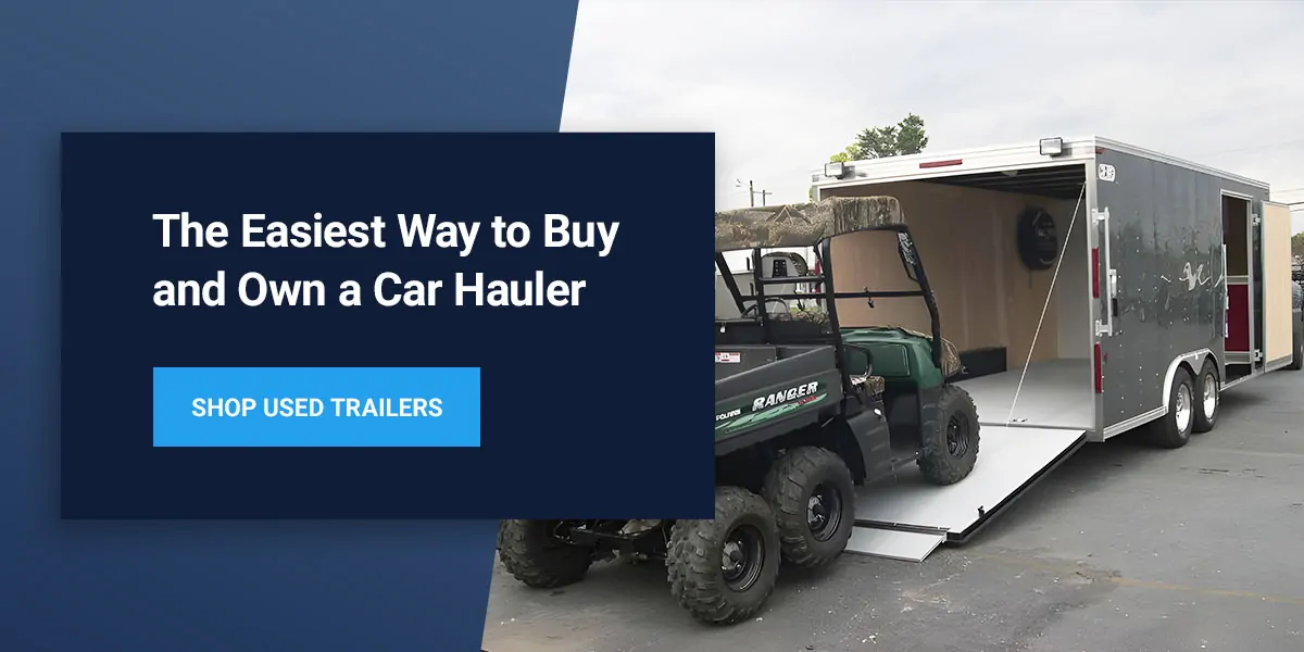 A car is being loaded onto an enclosed car trailer
